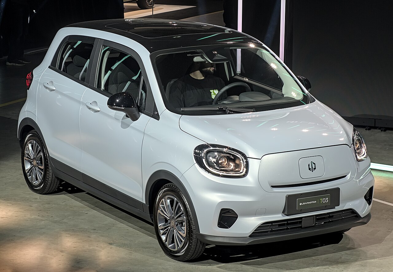 Coche eléctrico urbano pequeño aparcado en calle de ciudad europea